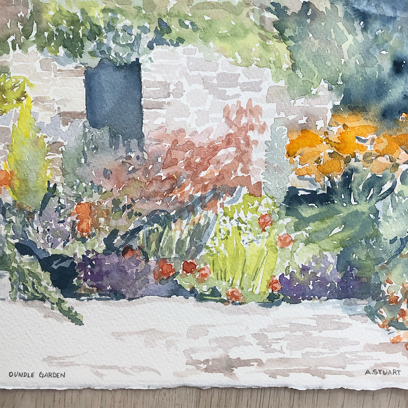 A colorful array of red, purple, and orange flowers amongst greenery in front of a light stone cottage