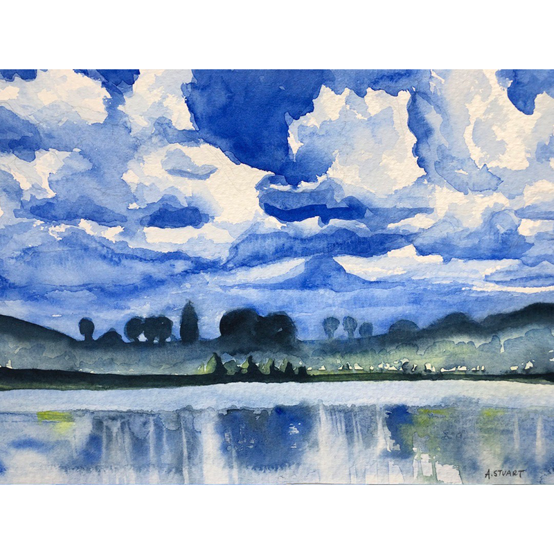 Deep royal blue color details white clouds in a vast sky, reflected onto the lake with dark indigo trees dividing the two